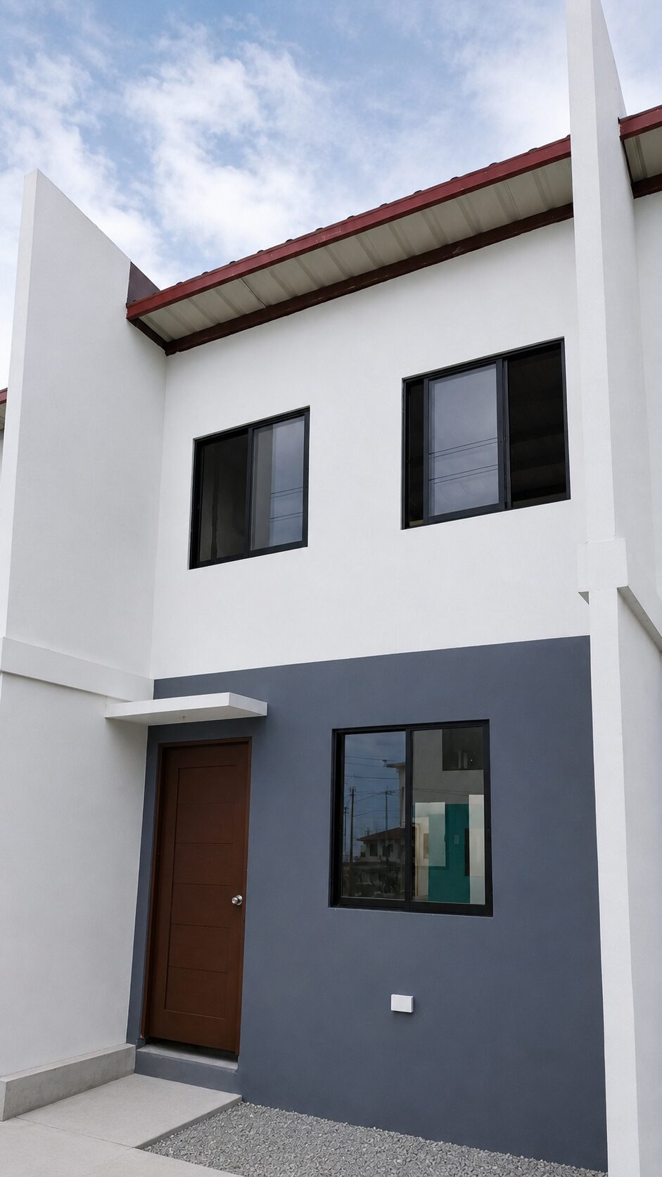 Front elevation of an economic unit at Arira Homes Babag, white above and slate grey below with a brown door