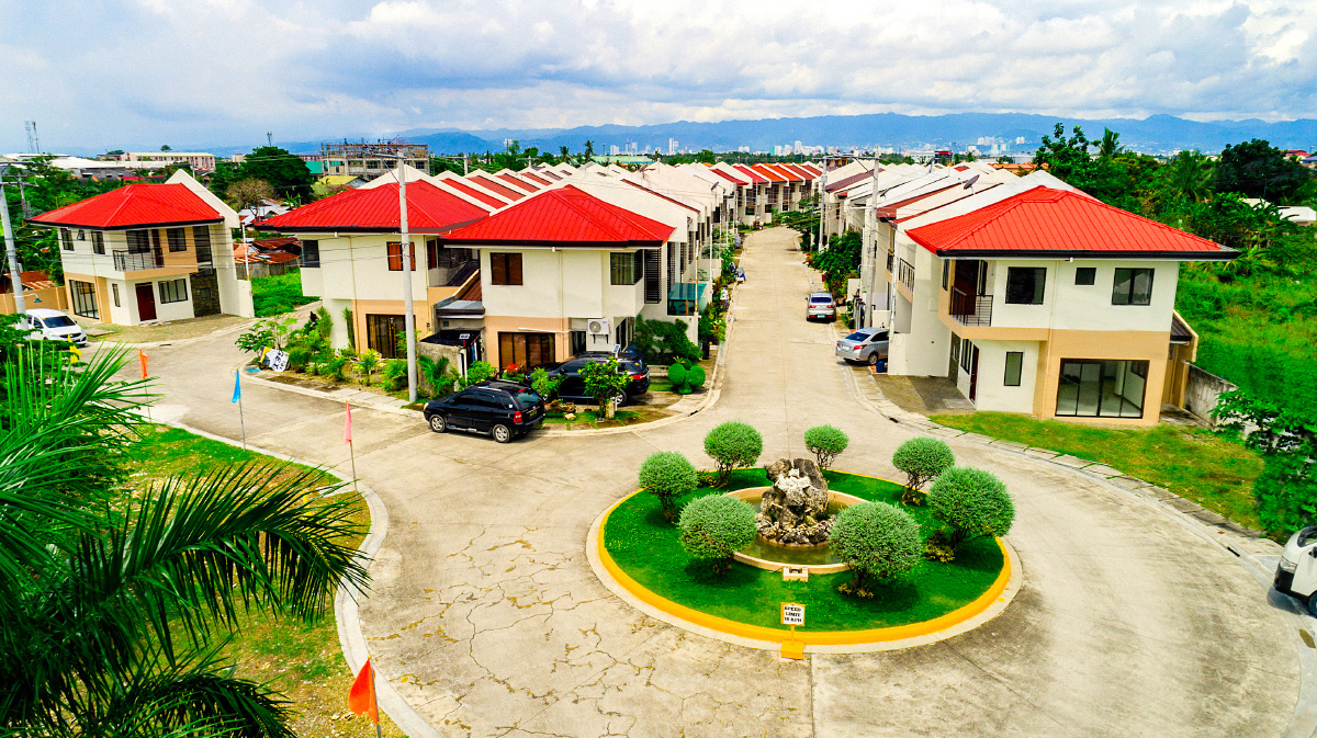 Houses around a landscaped roundabout at Anami Homes Mactan, with the hills behind