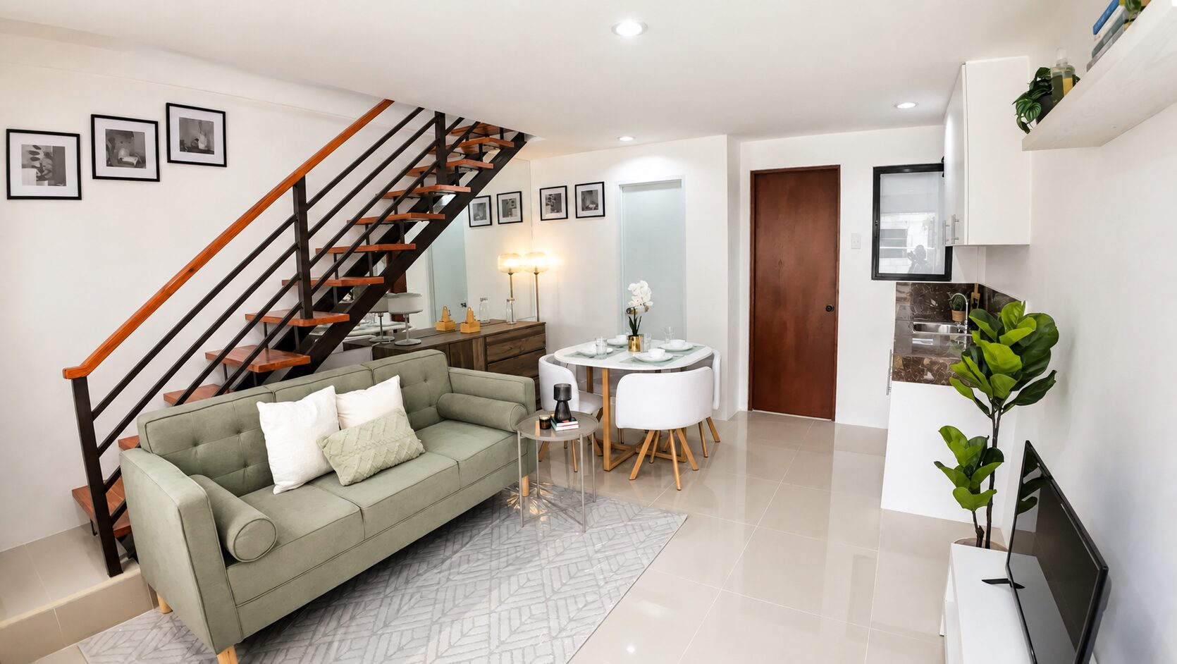 Living and dining area of an economic unit at Arira Homes Babag, with an open staircase and a kitchen counter beyond