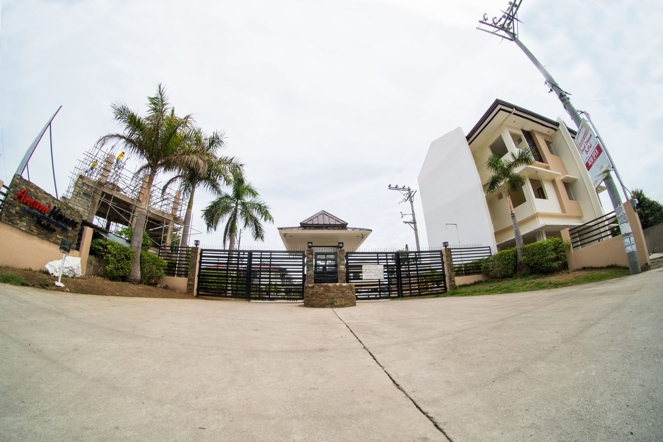 The entrance gate at Anami Homes Mactan seen from inside the subdivision, framed by palms